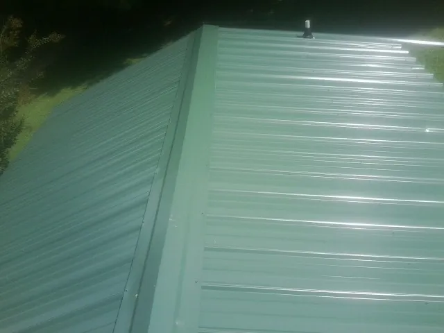 New green metal panels meeting at the ridge of a roof — Flat Roof Repair work by our crew in Craigmont
