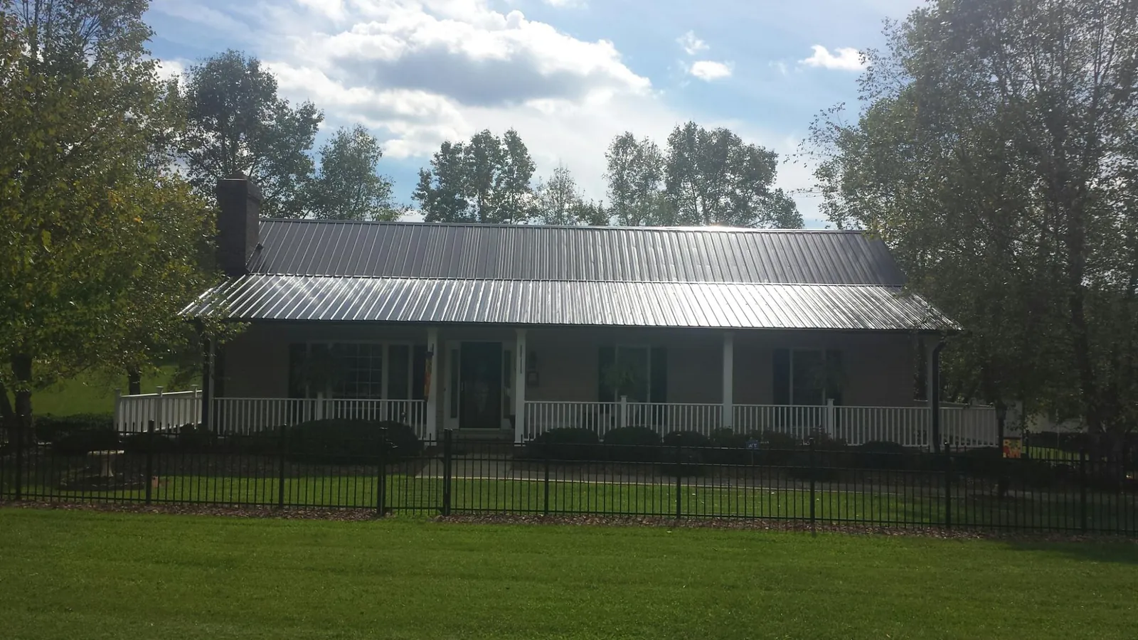 Gray metal roof on a brick ranch with a full width front porch — Gutter Guard Installation work by our crew in Craigmont