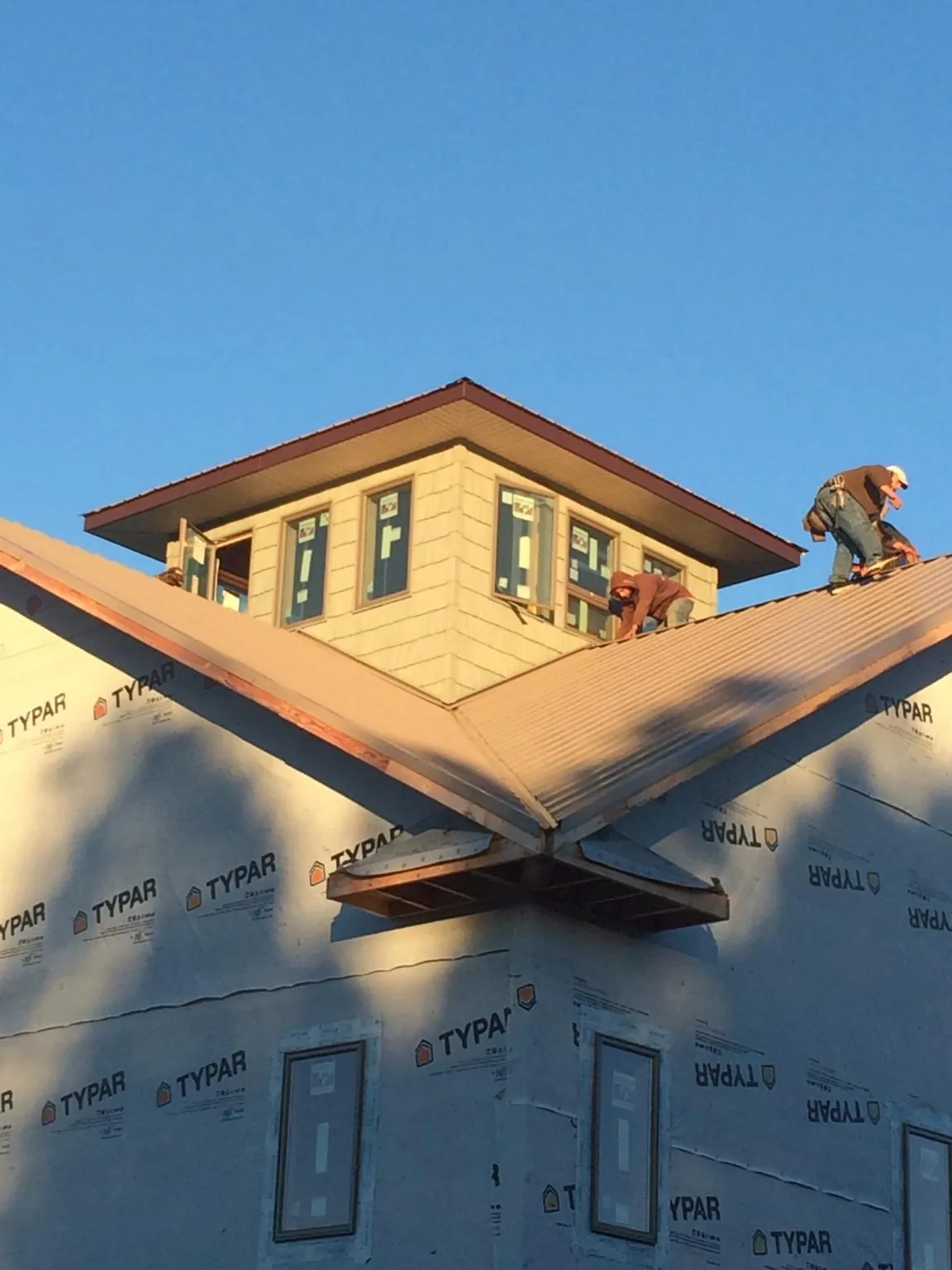 Roofers working around a rooftop cupola on a new metal roof at sunset — Roof Waterproofing in Craigmont by Roofing Brothers